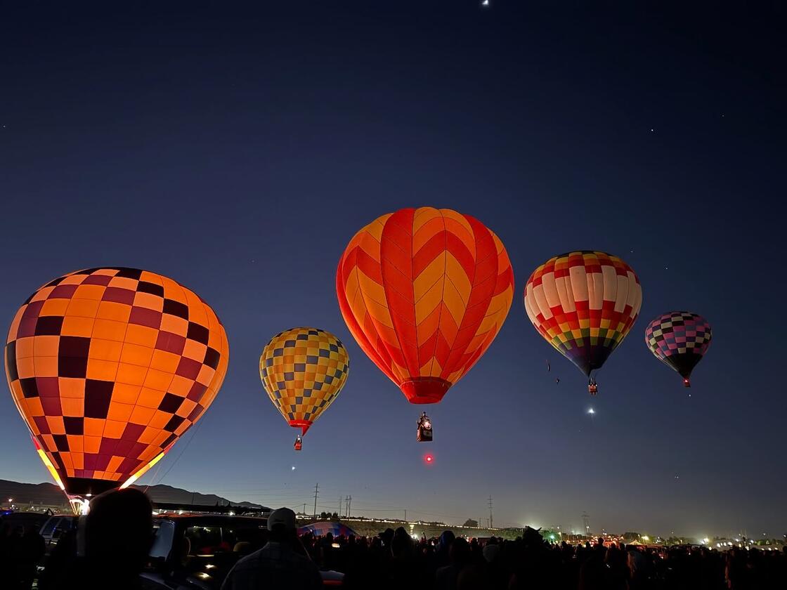 Hot air balloons lit against a night sky