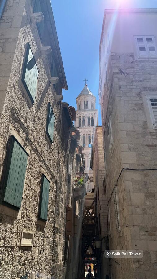 A stone alley opening onto a bell tower