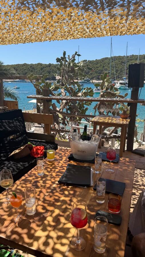 A long table set for dinner above the water at golden hour